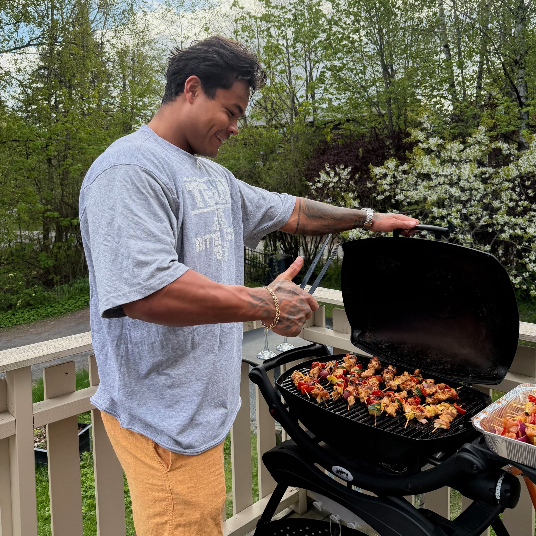 Coachen griller kyllingspyd på en grill på terrassen